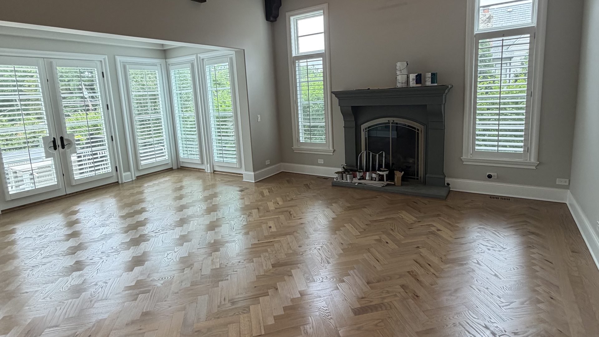 Red oak herringbone hardwood floor installed in a vaulted great room with exposed beams and a stone fireplace